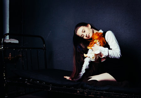pretty girl with an old doll in an abandoned building