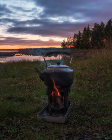 Camping Kettle on a campfire in nature overlooking the lake and sunset