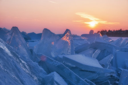 The winter sun sets over a frozen lake at sunset, with a characteristic natural phenomenon called hummocks.の写真素材