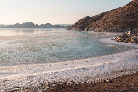 The freezing Kapchagai reservoir with hummocks of ice and mountains at sunset.の写真素材