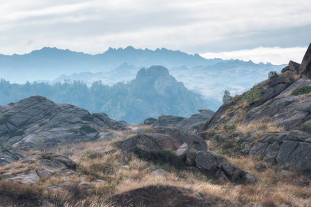 Scenic view of layered granite cliffs in Eastern Kazakhstan. In the foreground is a rocky landscape...