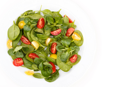 Spinach salad with cherry tomato on a white plateの写真素材