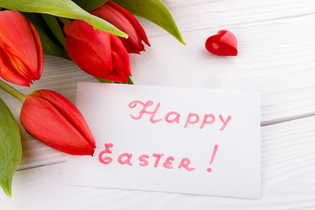 Red tulips and greetings card on white wooden boardの写真素材