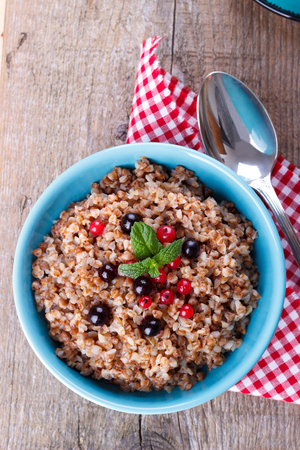 Buckwheat porridge in a bowl with red currant and blueberriesの写真素材