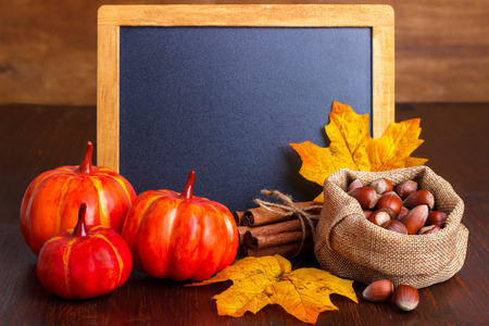 Autumn still life arrangement of pumpkins, nuts and yellow leaves around a blank vintage chalk boardの写真素材