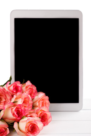 Tablet and bouquet of pink roses on white background. Space for textの写真素材