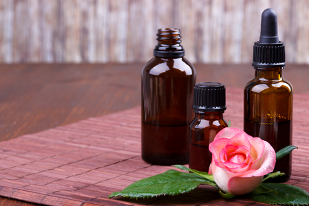 Pink rose essential oil bottles on brown backgroundの写真素材