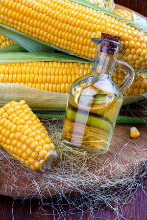 Fresh corn with bottle of oil on wooden backgroundの写真素材