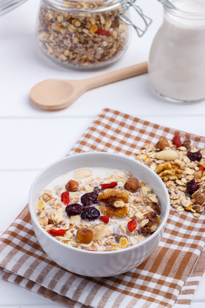 bowl of homemade muesli with nuts berries dried fruits milk and honey on white wooden background healthy breakfast top viewの写真素材