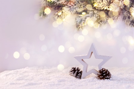 Wooden star on snow with pine tree branch and festive lights,Christmas or new year greetings cardの写真素材