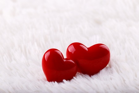 Valentines day concept.Two red hearts on white fur backgroundの写真素材