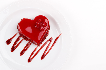 Heart shaped red velvet cake decorated with red currant on white plate, overhead viewの写真素材