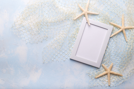 Summer Holiday concept with star fish, sea shells, fishing net and rope on blue background, flat lay, copy space for textの写真素材