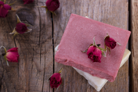 Natural hand made soap with dry pink roses on vintage wooden background spa settingの写真素材