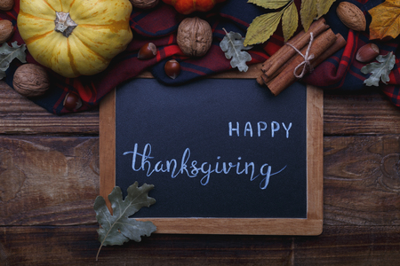 Happy thanksgiving text on black background with pumpkin nuts cinnamon and aoutumn dried leavesの写真素材