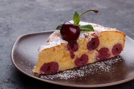 Home made cherry pie with icing sugar and mint over black rustic backgroundの写真素材