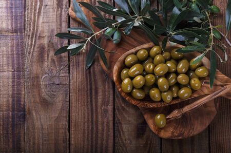 Green marinated salted mediterranean olives in a bowl on dark wooden backgroundの写真素材