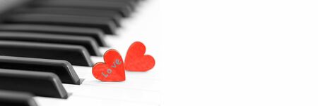 Romantic concept, piano and red wooden hearts, close up bannerの写真素材