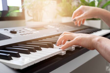 Woman playing on synthesizer, MIDI keyboard piano, home learning, music education