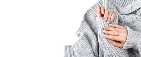 Manicured woman hands with pastel nail polish, grey knitted background, close up banner with copy spaceの写真素材