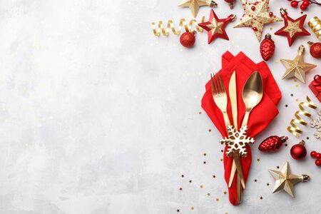 Christmas or new year table setting with golden cutlery and red napkin on white stone table, card or menu template copy space flat layの写真素材