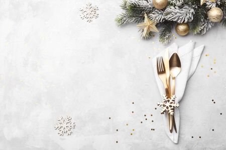 Christmas or new year table setting with golden cutlery on white stone table, card or menu template copy space flat layの写真素材