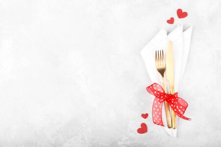 Romantic table setting with golden cutlery on white stone table.Valentine's day card templateの写真素材