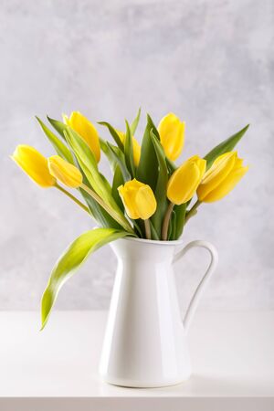 Bouquet of yellow tulips in a pitcher on grey stone background top view, flat lay copy spaceの写真素材