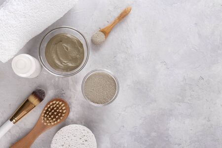 Cosmetic clay powder for skin and hair, spa and wellness, natural cosmetics and brushes on light grey background with copy spaceの写真素材