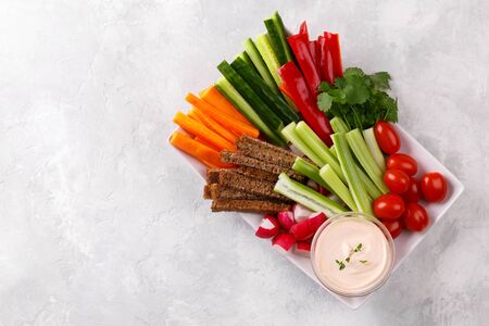 Healthy vegetables snack with yoghurt sauce on a grey stone background, top view close up, copy spaceの写真素材
