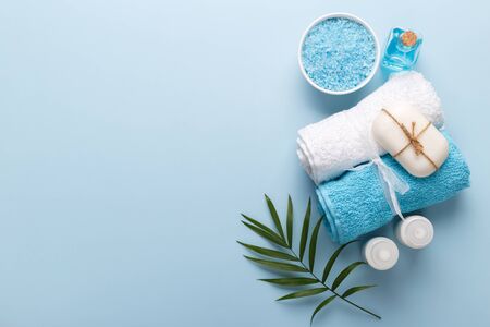 Spa setting, aromatherapy health and wellness on blue background, copy space flat lay, blue sea salt, oil, cream soap,towelsの写真素材
