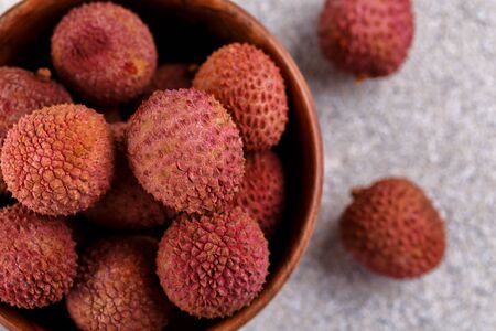 Ripe healthy lychee fruit in a wooden bowl on grey stone background with copy spaceの写真素材