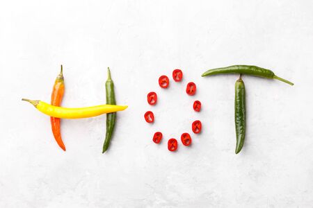 Word Hot made of red green and yellow chili peppers on grey stone backgroun  top viewの写真素材
