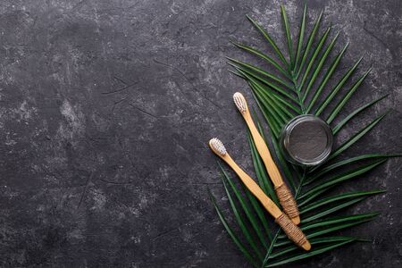 Natural bamboo tooth brushes and black dental powder on dark grey background, zero waste products,...