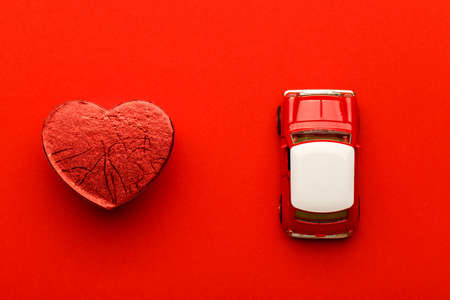 Red small toy car and heart on vibrant background, postcard conceptの写真素材
