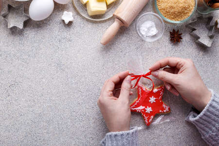 Winter holidays baking ingrediends and womanâ€™s hands with star shape cookie on grey stone...