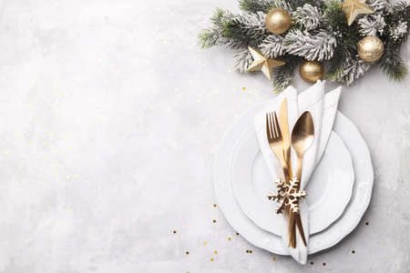 Christmas or new year table setting with golden cutlery on white stone table, card or menu template copy space flat lay