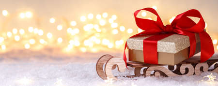Golden gift box with red ribbon on the sleigh, Christmas or new year greetings card with copy space,...