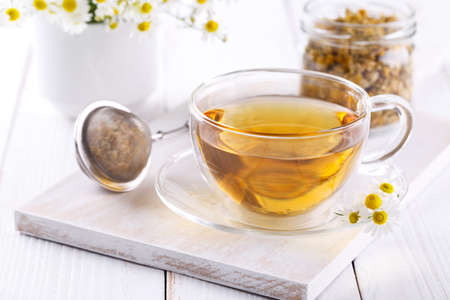 Healthy chamomile tea in a glass teacup on white wooden background copy spaceの写真素材