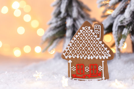 Christmas or New Year homemade gingerbread cookie house shaped, fir tree on the snow, festive greetings cardの写真素材