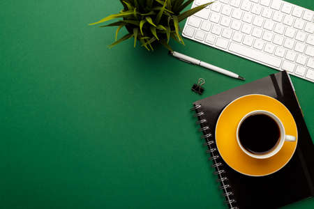 Student, business or freelancer workspace with keyboard, coffee, notepad, pen and pencils on green background, flat lay. Space for textの写真素材