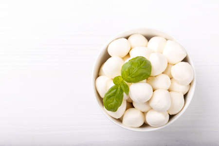 Mozzarella cheese and basil on white wooden board copy space. Ingredients for Caprese saladの写真素材