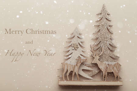 Christmas or new year card, Wooden deers and pine tree on beige trendy background with greeting Merry Christmas and Happy new yearの写真素材