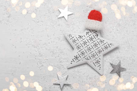 Christmas or new year greetings card template with copy space, white wooden background with festive star decoration and red hatの写真素材