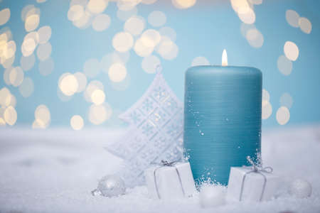 Christmas or new year candle with festive ornaments and bokeh lights on snow, family holidaysの写真素材