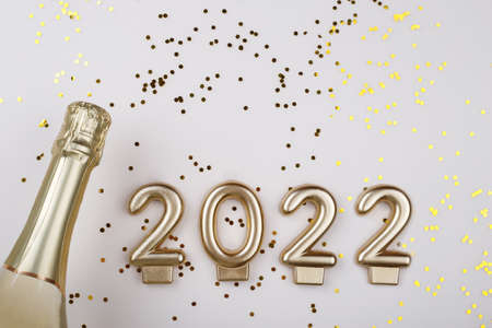 Flat lay composition of Champagne bottle and confetti on beige background copy space, new year 2022