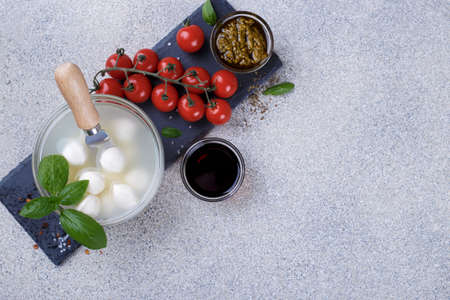 Mozzarella cheese, basil and tomato cherry on grey stone table copy space. Ingredients for Italian Caprese saladの写真素材