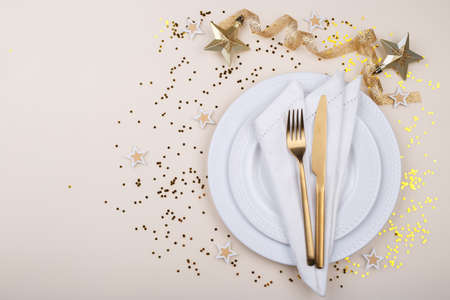 Christmas or new year table setting with golden cutlery and name card mockup on beige table, card or...
