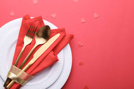 Romantic table setting, gold cutlery on the red table cloth. Valentine's day celebrationの写真素材