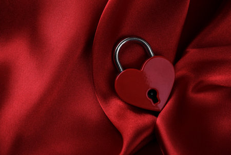 Heart shaped padlock on red silk background. Valentine's day concept. Symbol of love, copy spaceの写真素材